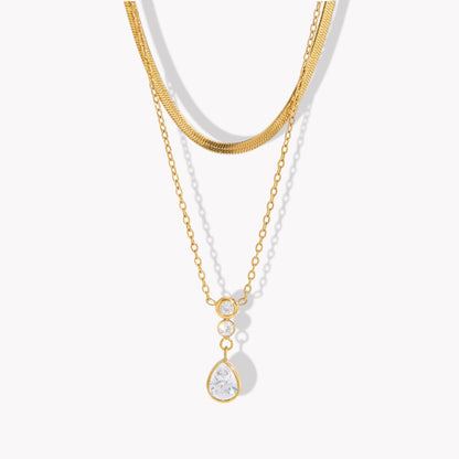 Double layer necklace featuring a top layer snake chain with bottom longer layer with pear shaped gemstone pendant pictured on a light background