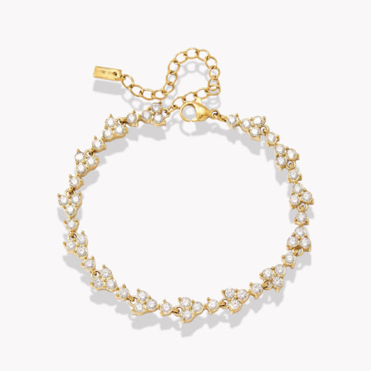 gold bracelet with gemstone details pictured on a light grey background