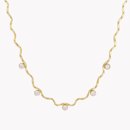 A delicate gold necklace with a wavy, twisted design and five small clear round gemstones spaced along the chain, shown against a plain white background.