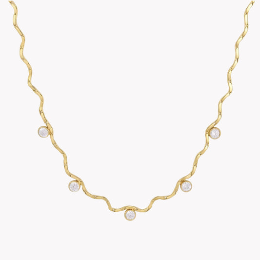 A delicate gold necklace with a wavy, twisted design and five small clear round gemstones spaced along the chain, shown against a plain white background.