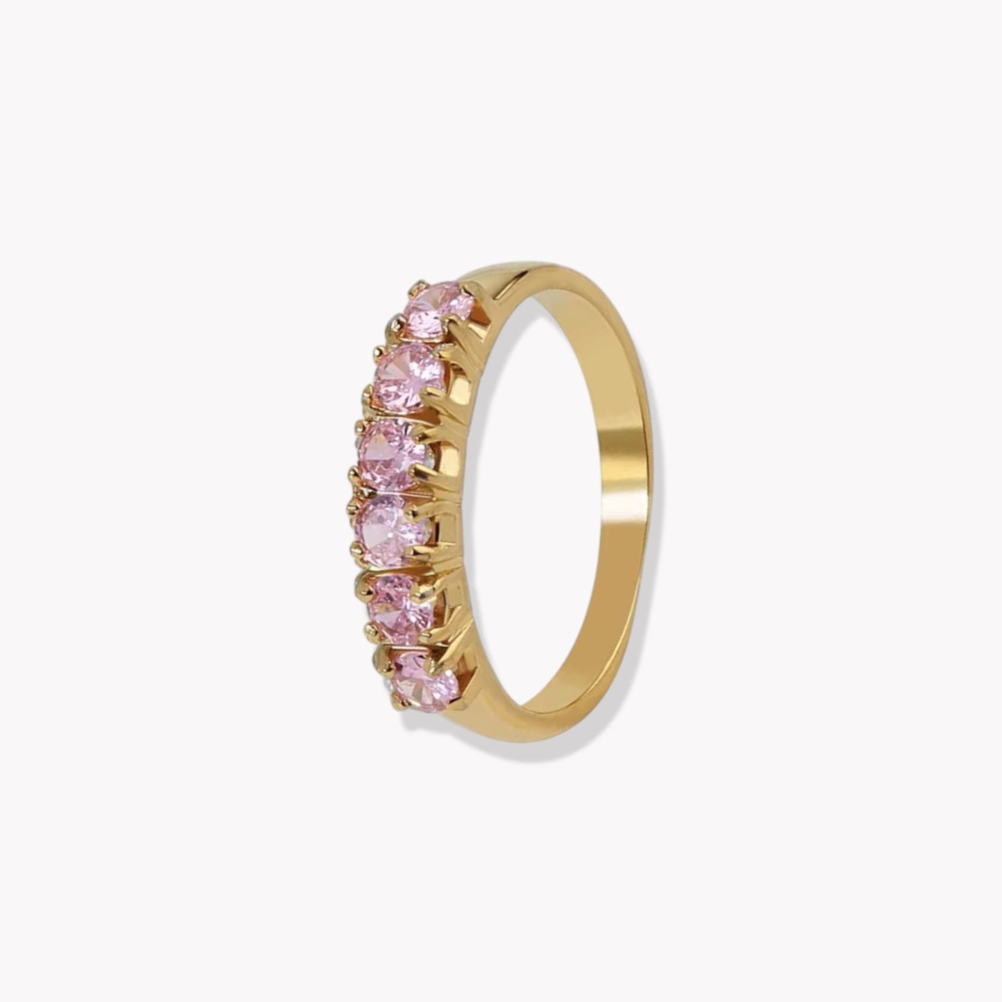 Gold ring with pink gemstones on a white background