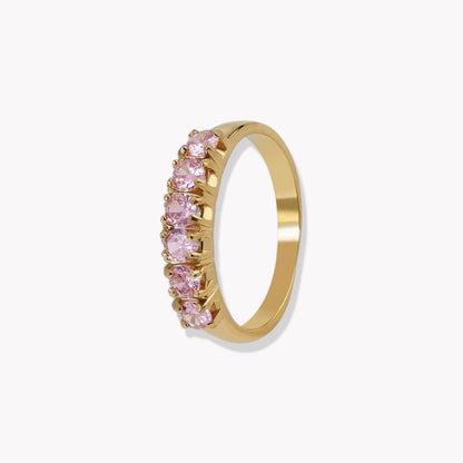 Gold ring with pink gemstones on a white background