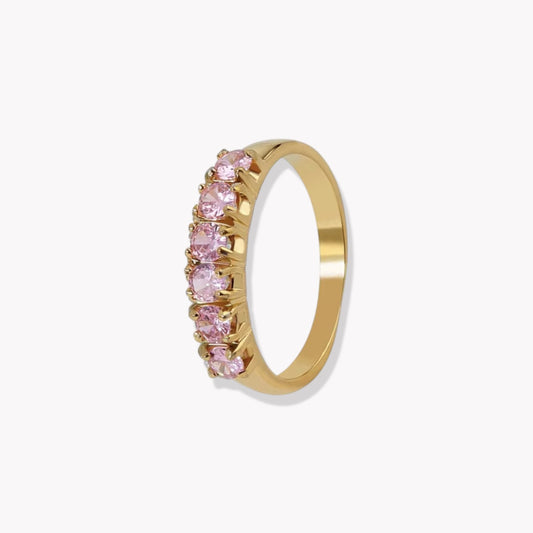 Gold ring with pink gemstones on a white background