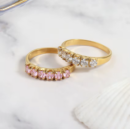 Two gold rings with gemstones on a marble surface
