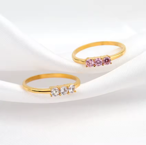 Two gold rings with gemstones on a white background
