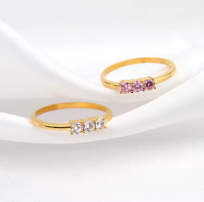 Two gold rings with gemstones on a white background