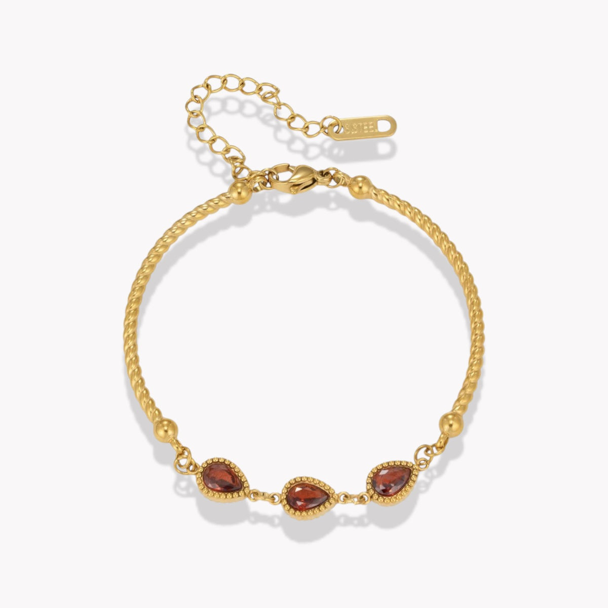 A gold chain bracelet with three teardrop-shaped garnet stones, displayed on a clean white background.