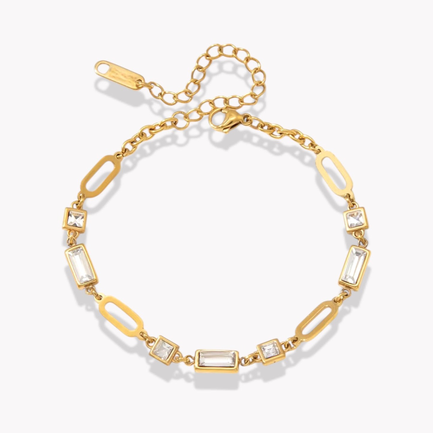 gold bracelet with gemstones pictured on a light grey background