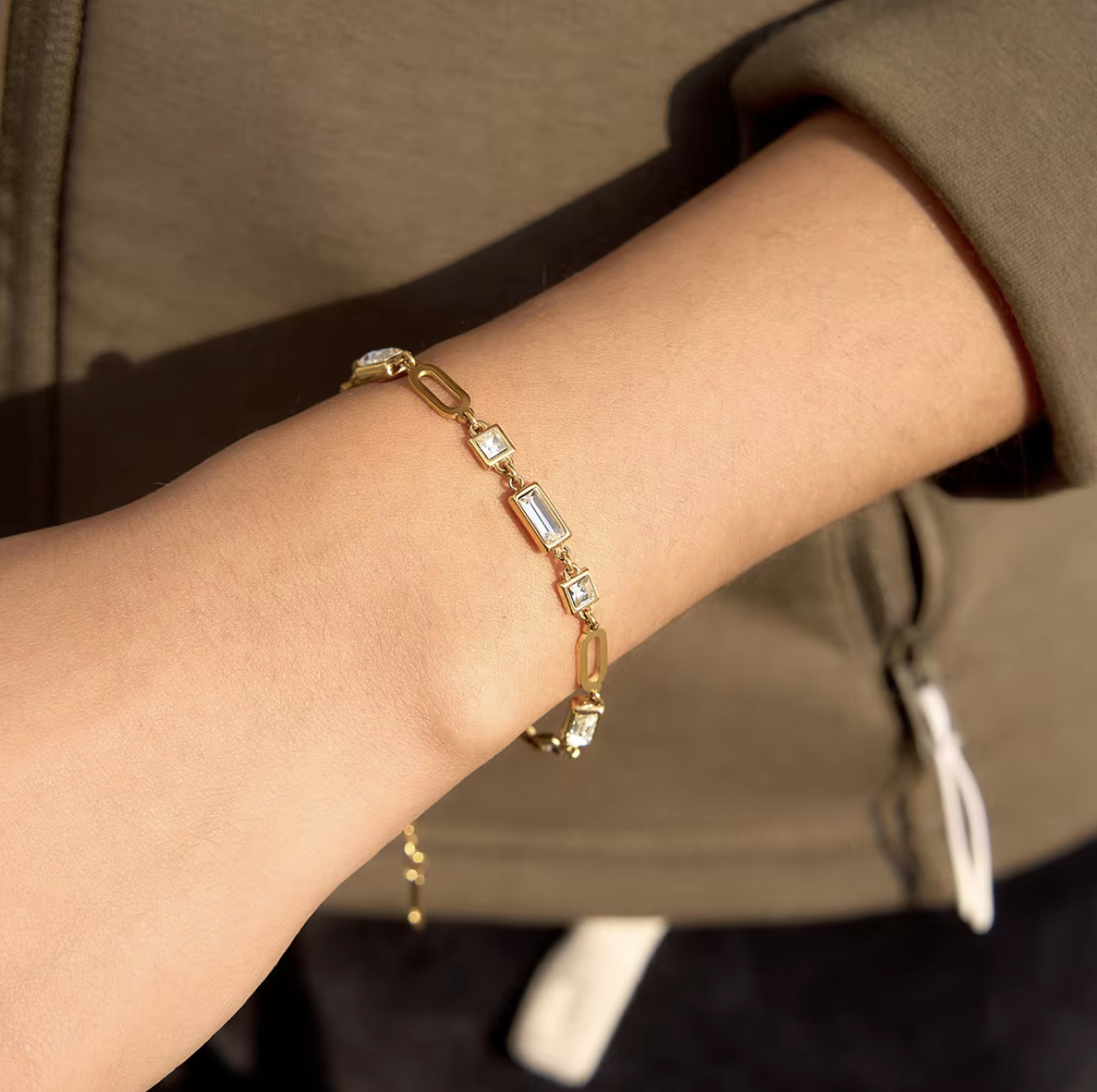 gold bracelet with gemstones pictured being worn on a wrist