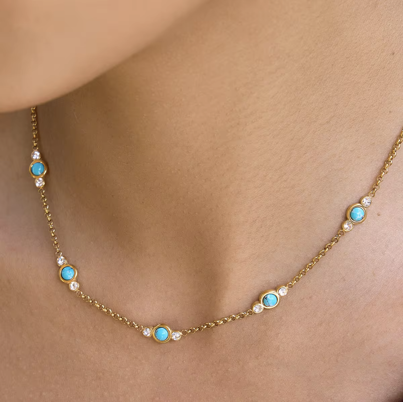 Gold necklace with turquoise stones on a person's neck