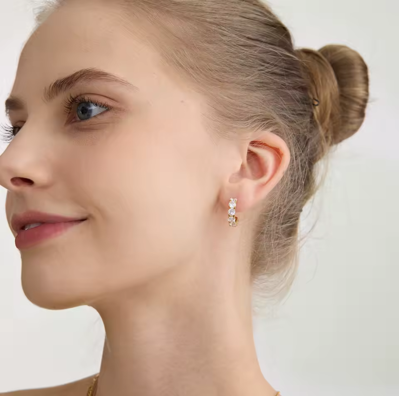 Close-up of a woman wearing diamond earrings with a plain background
