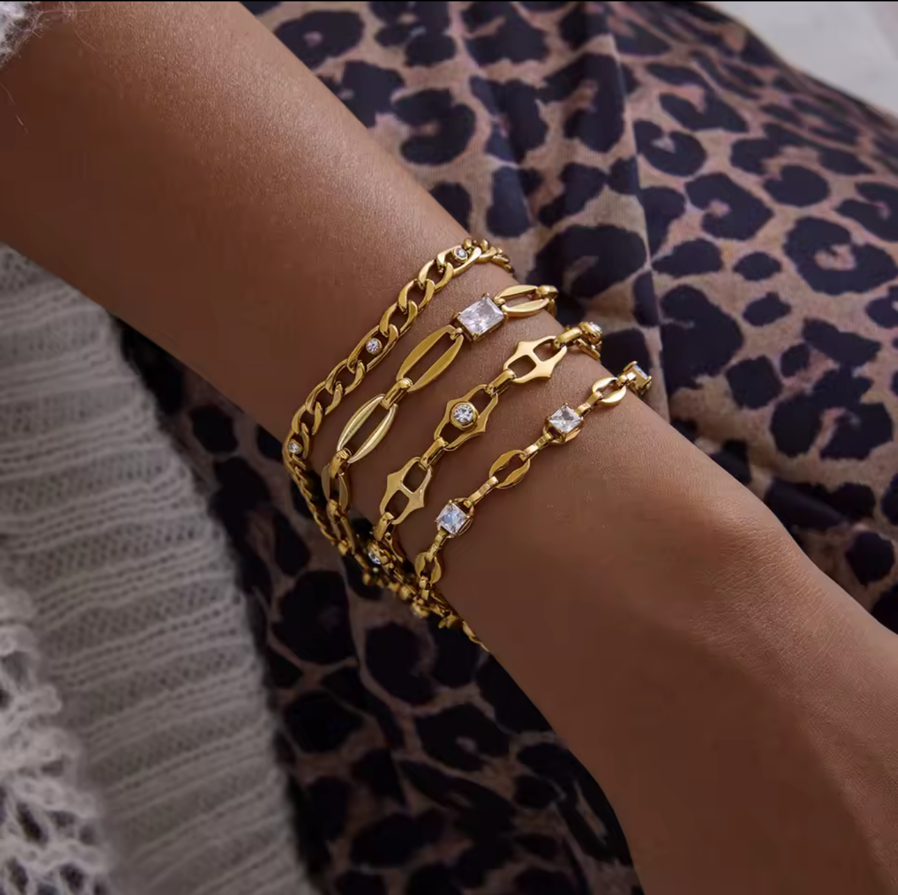 Gold bracelets on a wrist with a leopard print fabric background
