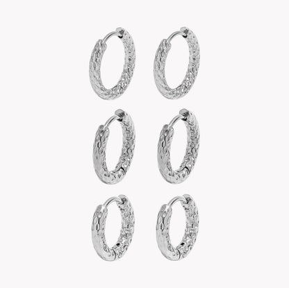 Six silver textured hoop earrings arranged in a 3-by-2 grid on a plain light gray background.