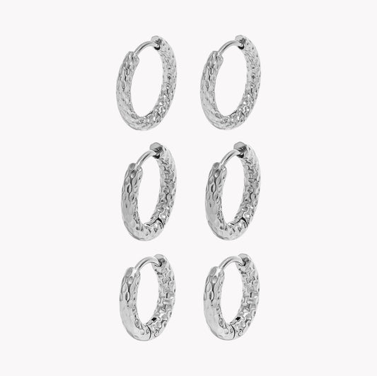 Six silver textured hoop earrings arranged in a 3-by-2 grid on a plain light gray background.