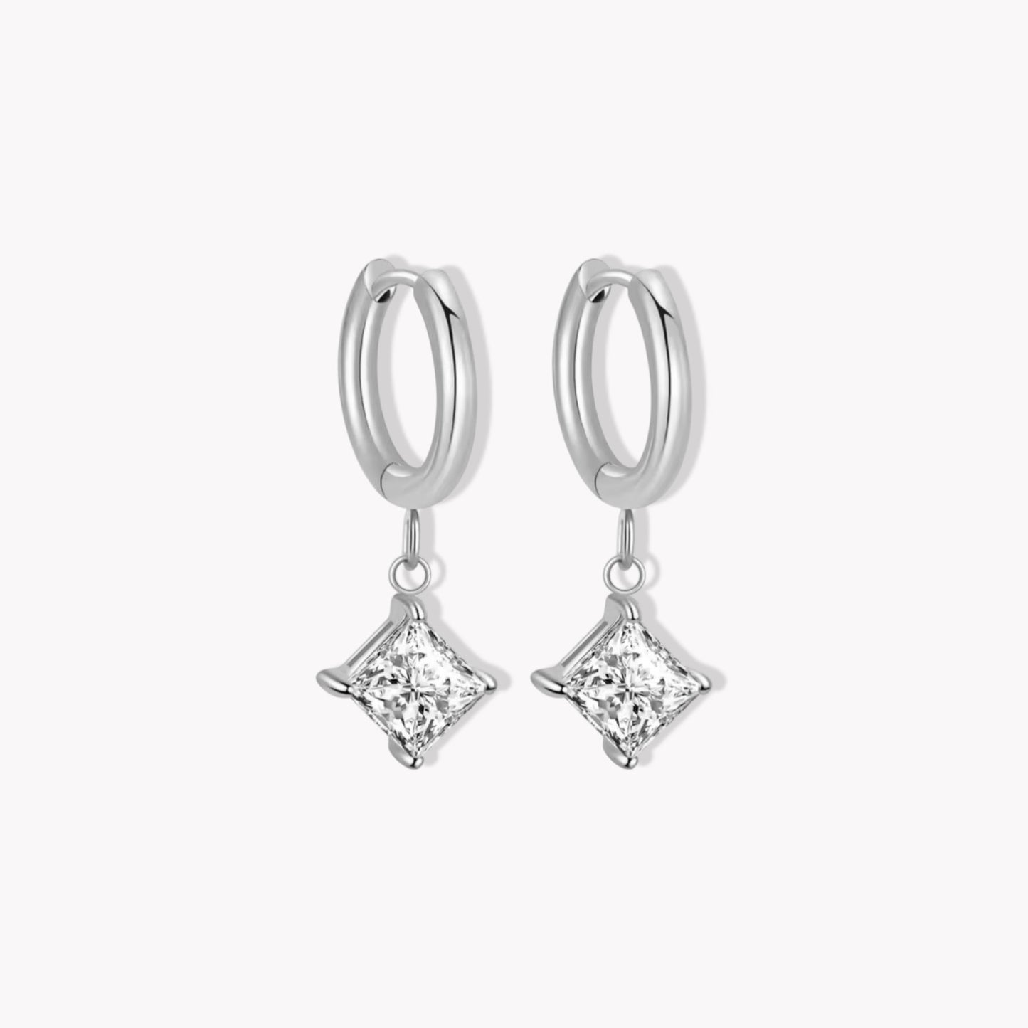 Silver hoop earrings with clear square shaped diamond pendants on a white background
