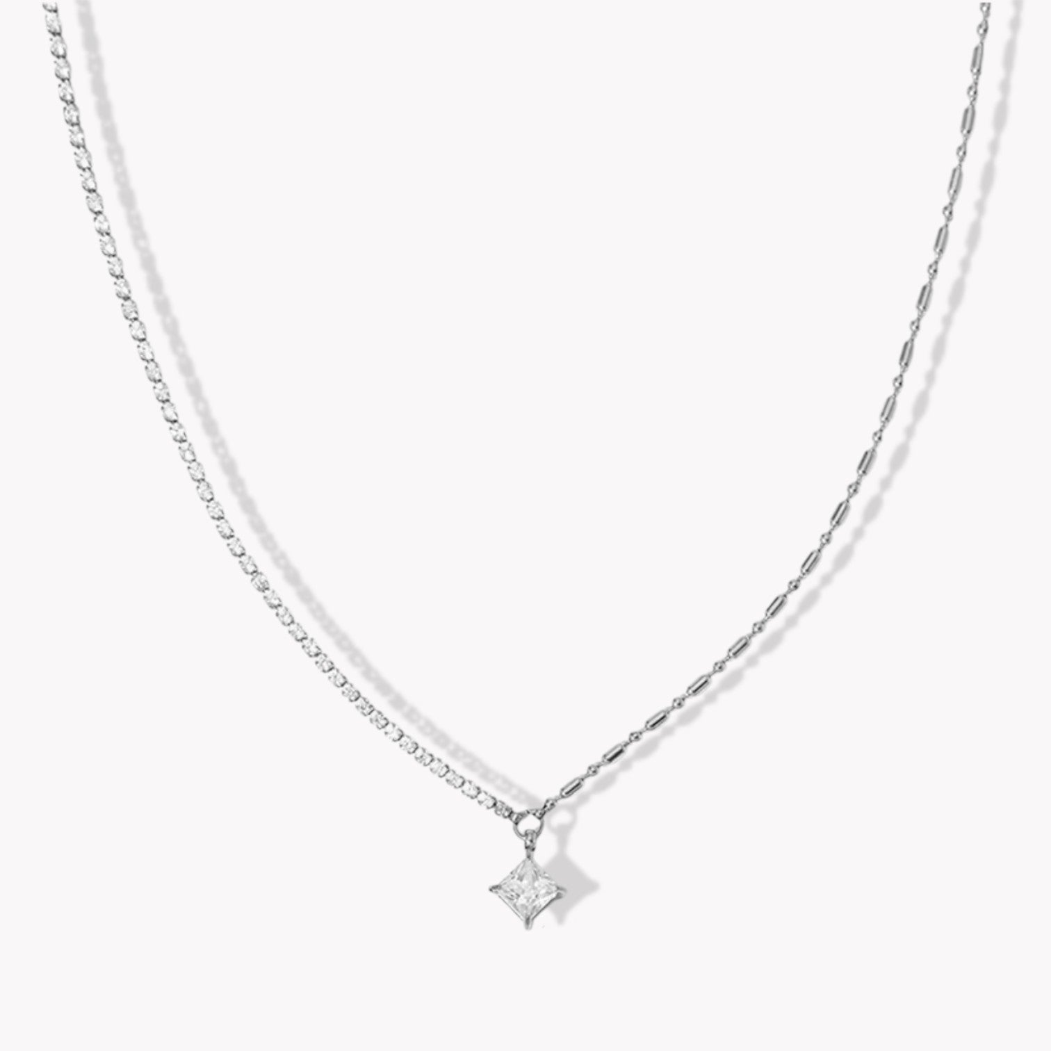 Silver necklace with a square shaped pendant on a white background