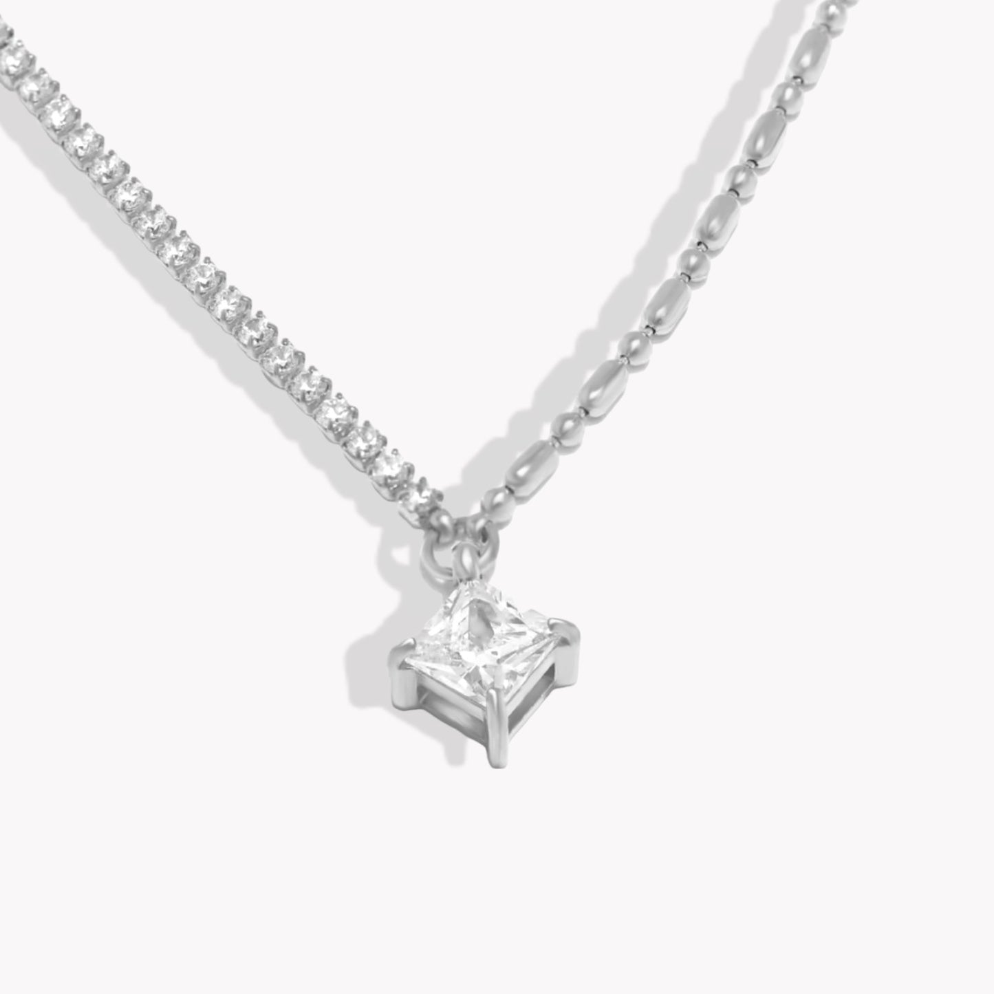Silver necklace with a square shaped diamond pendant on a white background