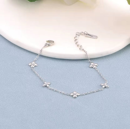 Silver bracelet with flower detail on a blue and white background
