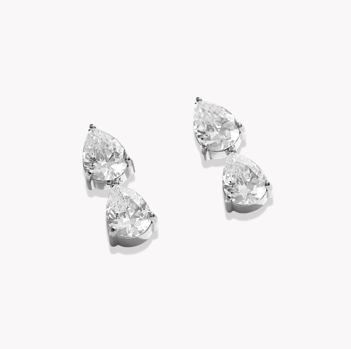 A pair of silver stud earrings featuring pear-cut clear gemstones in a prong setting, displayed on a clean white background.