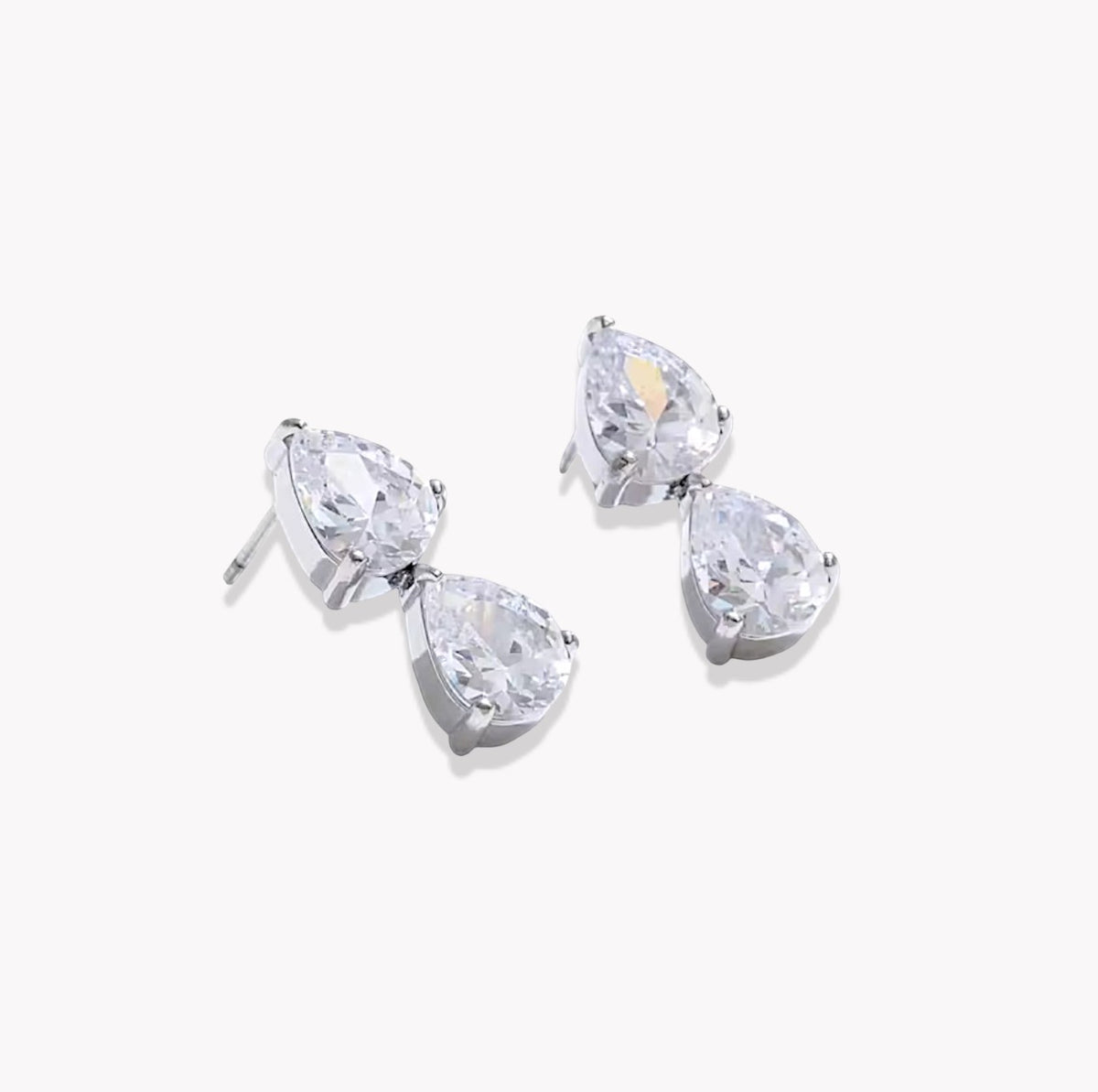 A pair of silver stud earrings featuring pear-cut clear gemstones in a prong setting, displayed on a clean white background.