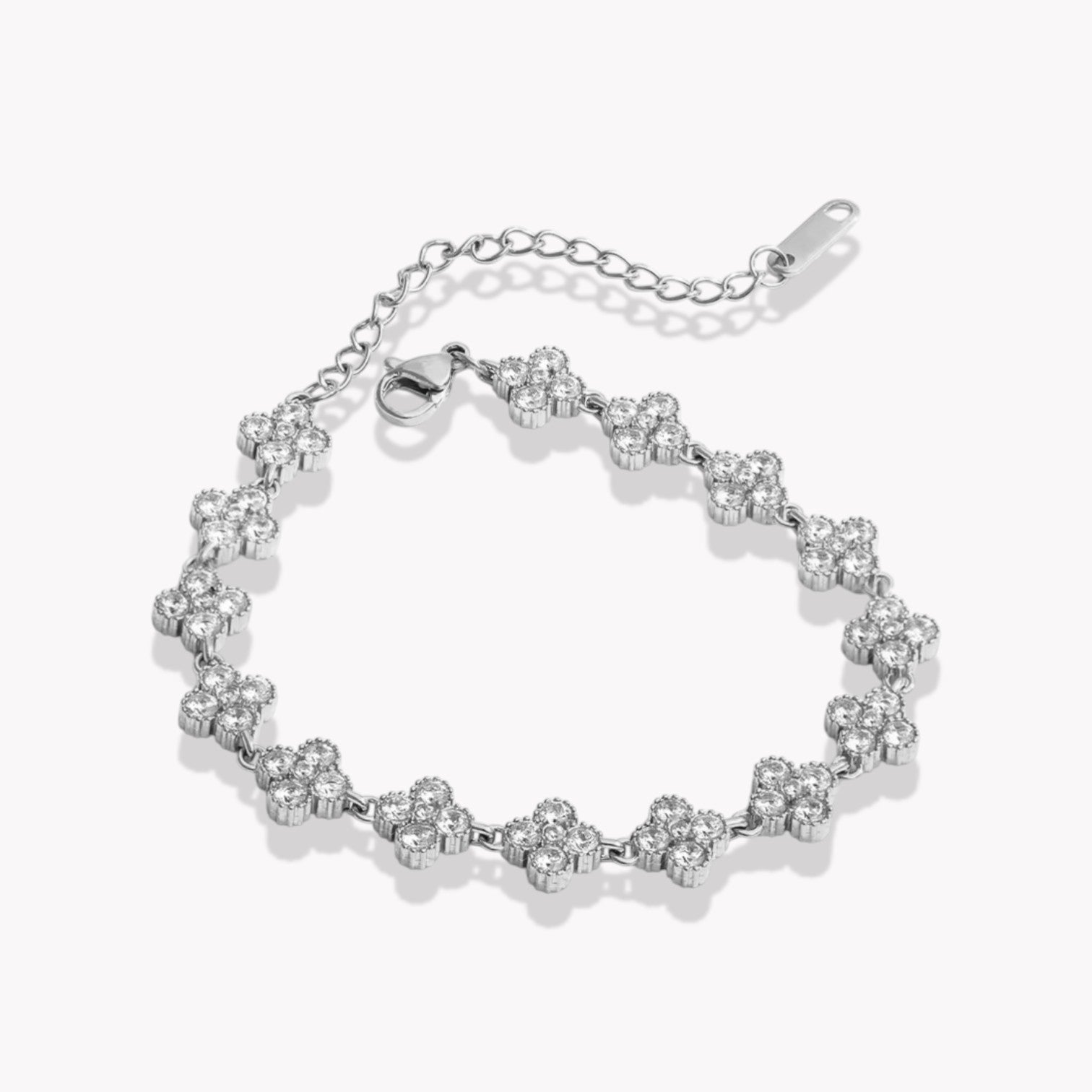 Silver bracelet with clear stones arranged in the shape of a four leaf clover on a white background