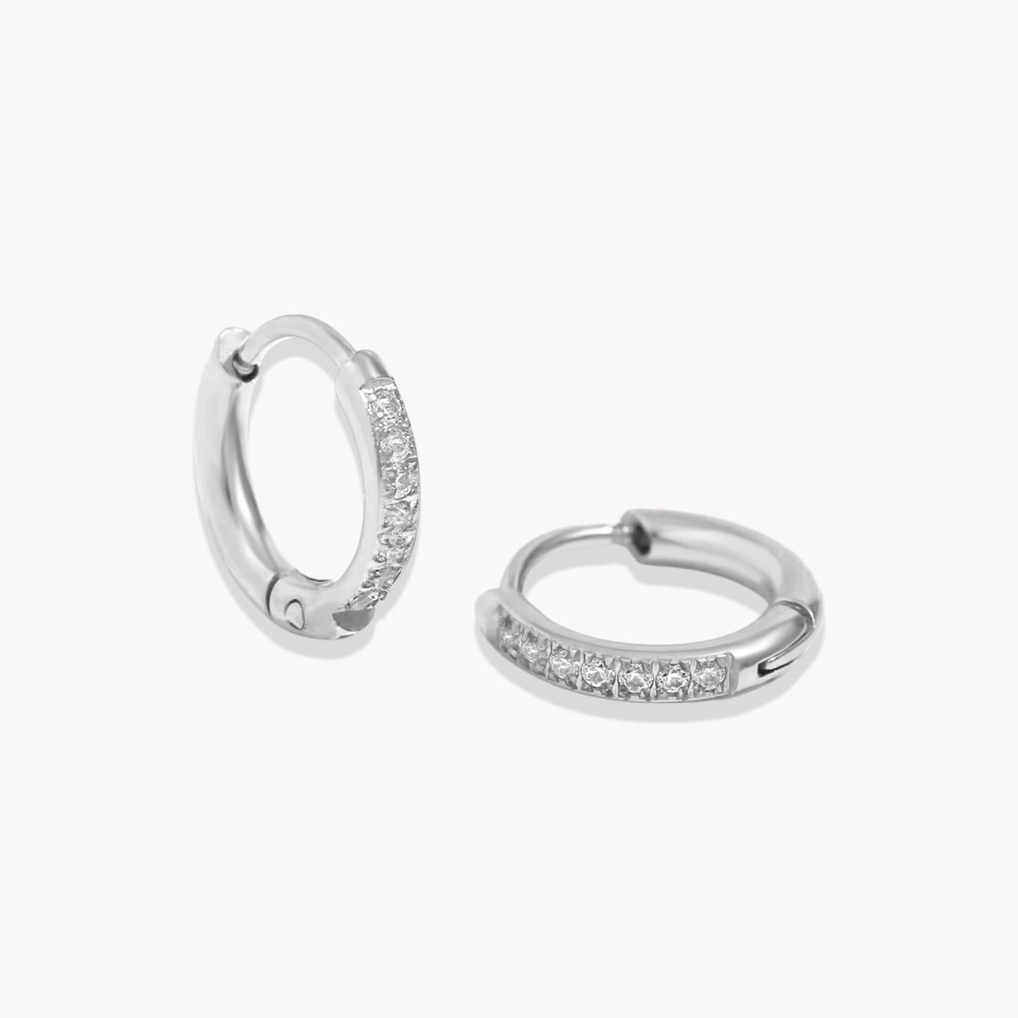 Silver crystal huggie hoop earring with a row of crystals around the hoop. pictured on a white background