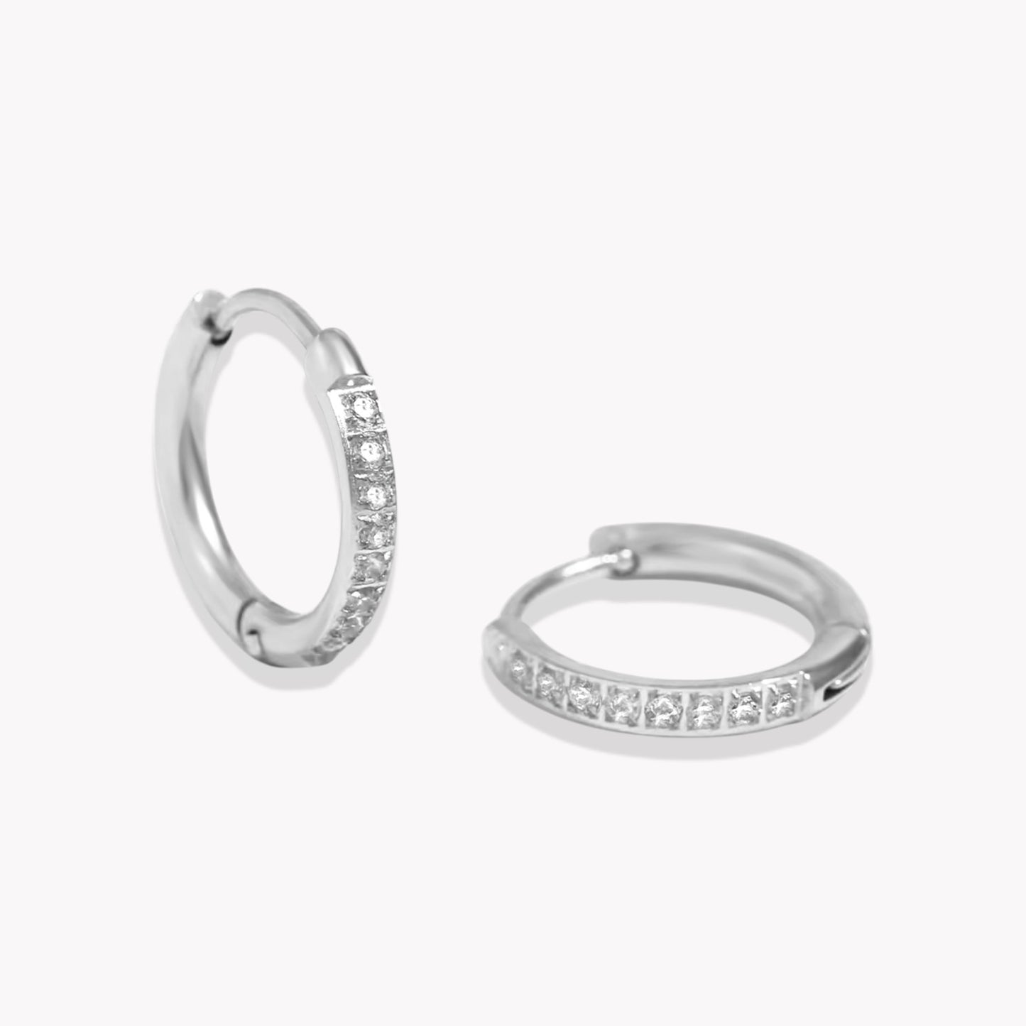 Silver crystal huggie hoop earring with a row of crystals around the hoop. pictured on a white background