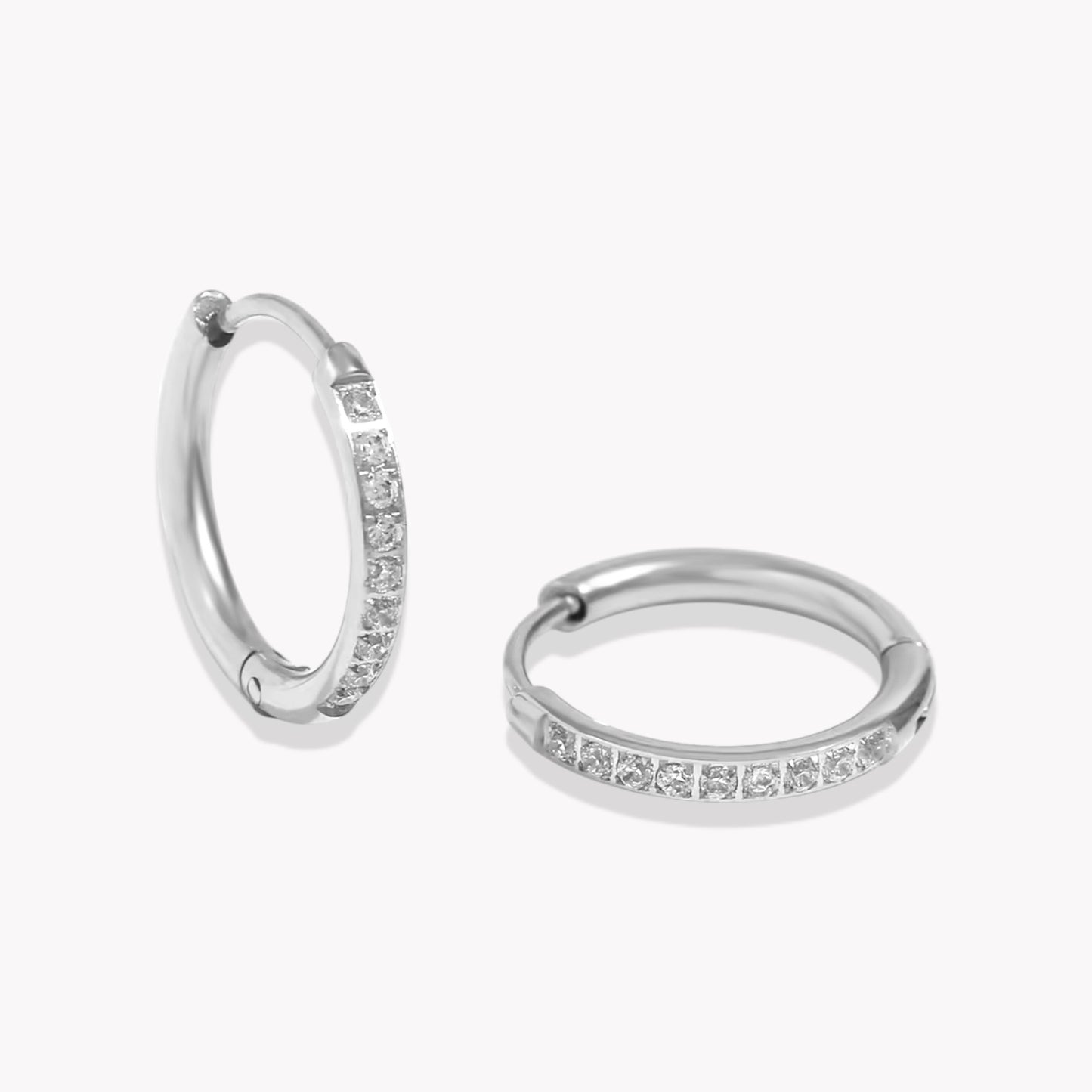 Silver crystal huggie hoop earring with a row of crystals around the hoop. pictured on a white background