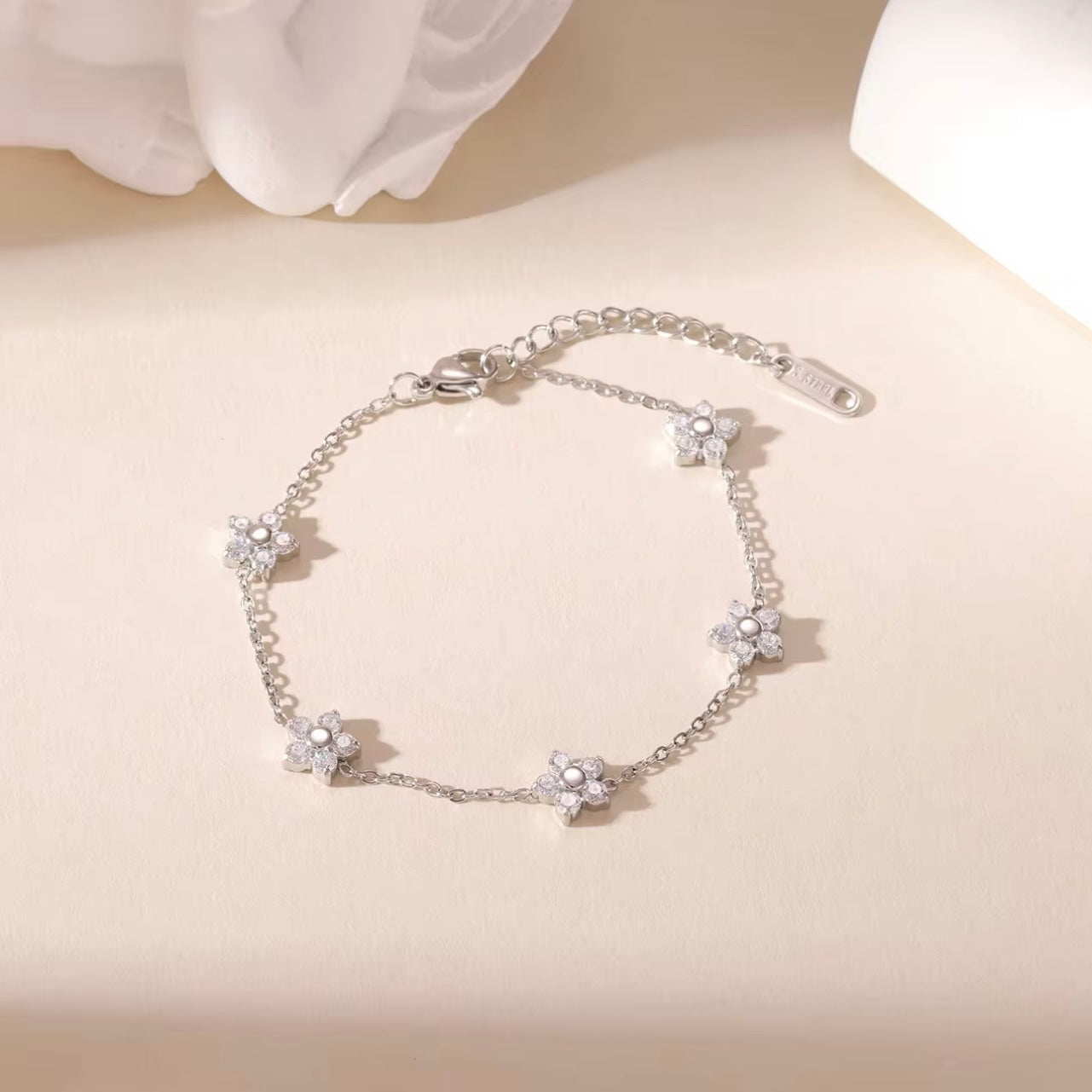 Silver bracelet with clear gemstone floral design on a beige background