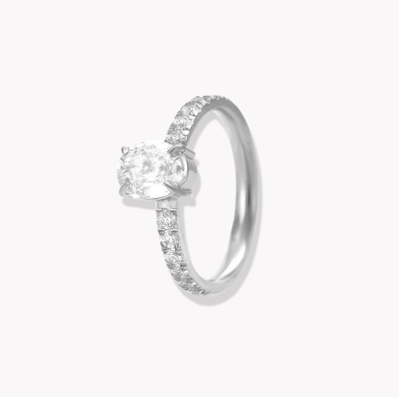 Silver ring with oval gemstone and further gemstones along the band of the ring, pictured on a light grey background