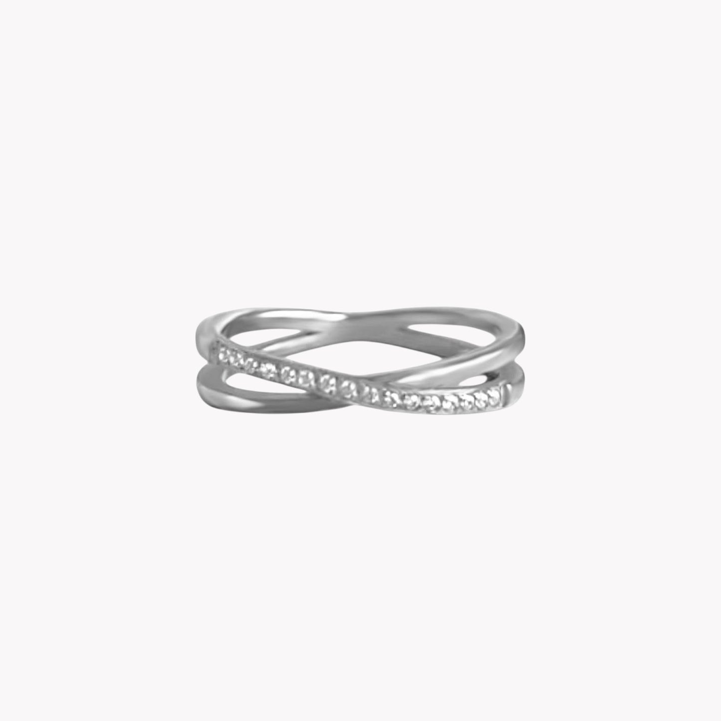 Silver ring with interlocking design and small clear gemstone on a white background