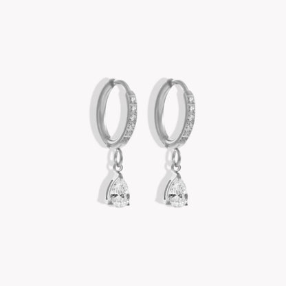Silver hoop earrings with diamonds on the hoop and a pear shaped drop pendant on a white background
