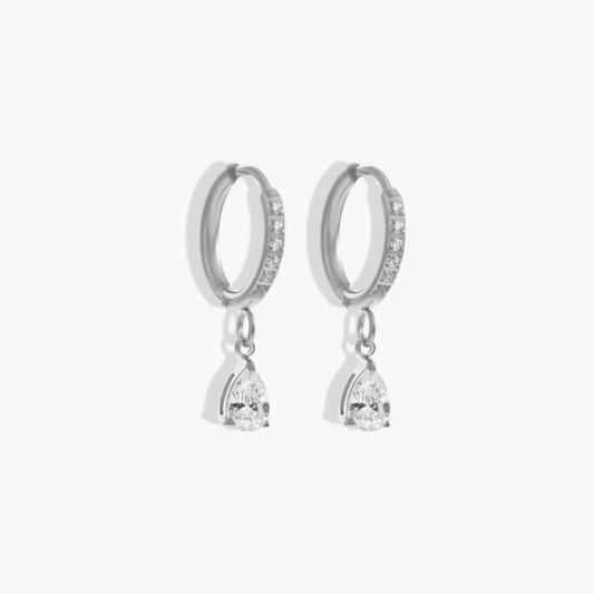 Silver hoop earrings with diamonds on the hoop and a pear shaped drop pendant on a white background