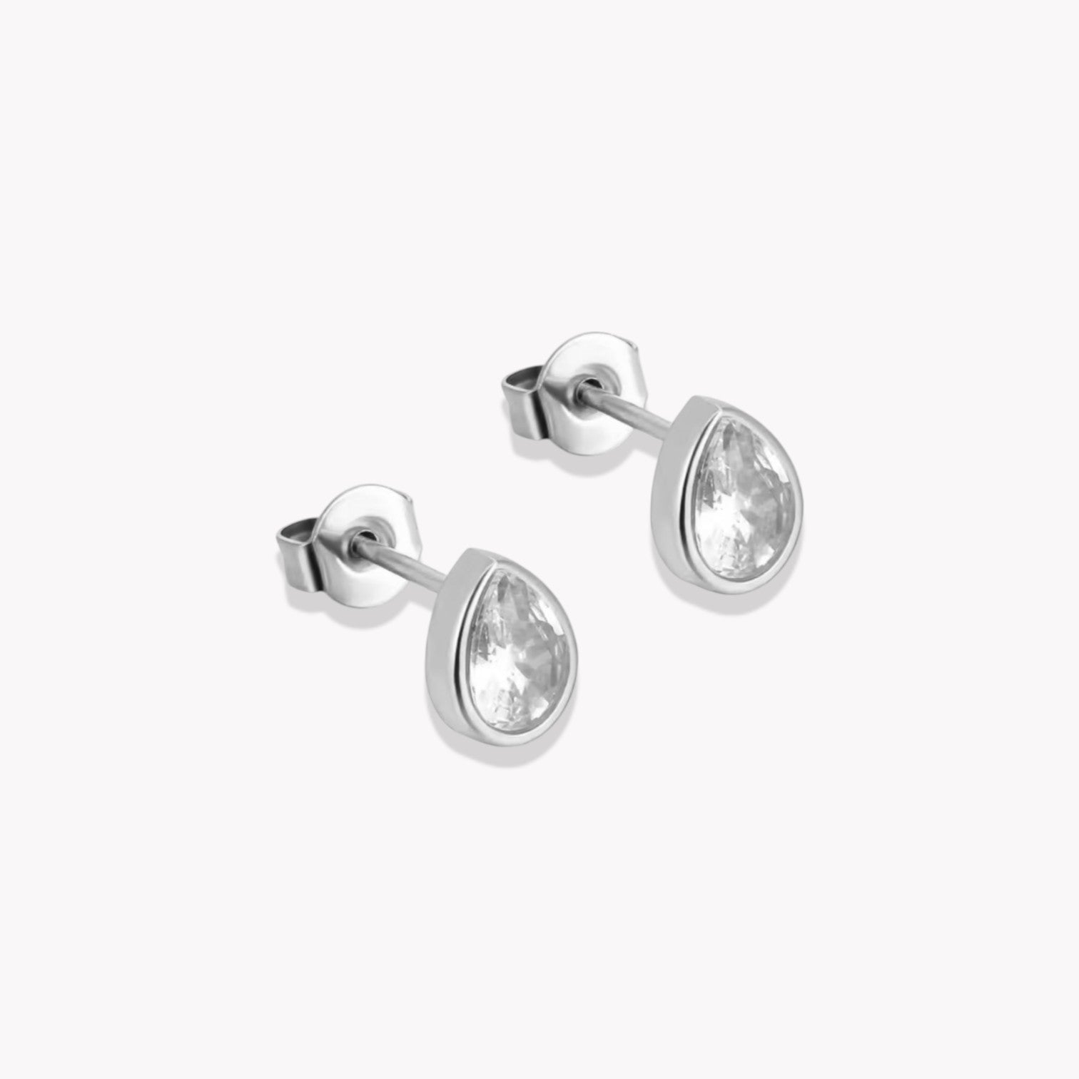 A pair of silver stud earrings with a pear shape and a central clear crystal, mounted on a white background.