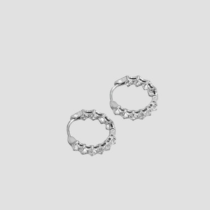 Pair of silver hooped earrings featuring beautiful clear gemstones onn the front and inside the back of the hoop. Pictured on a llight grey background