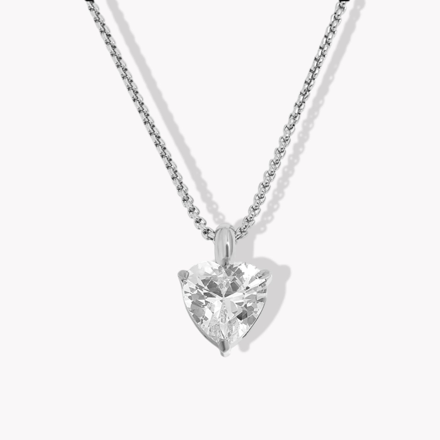 Silver Heart-shaped diamond pendant on a chain against a white background