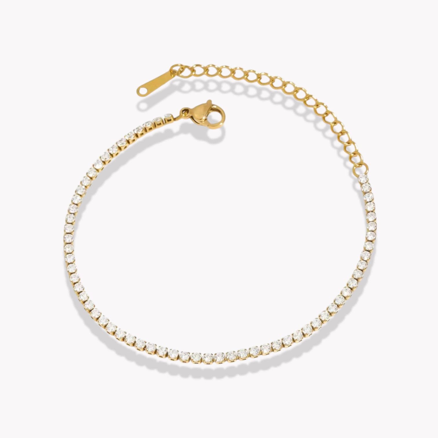 A slim tennis bracelet with small clear crystals throughout, featuring a gold clasp.