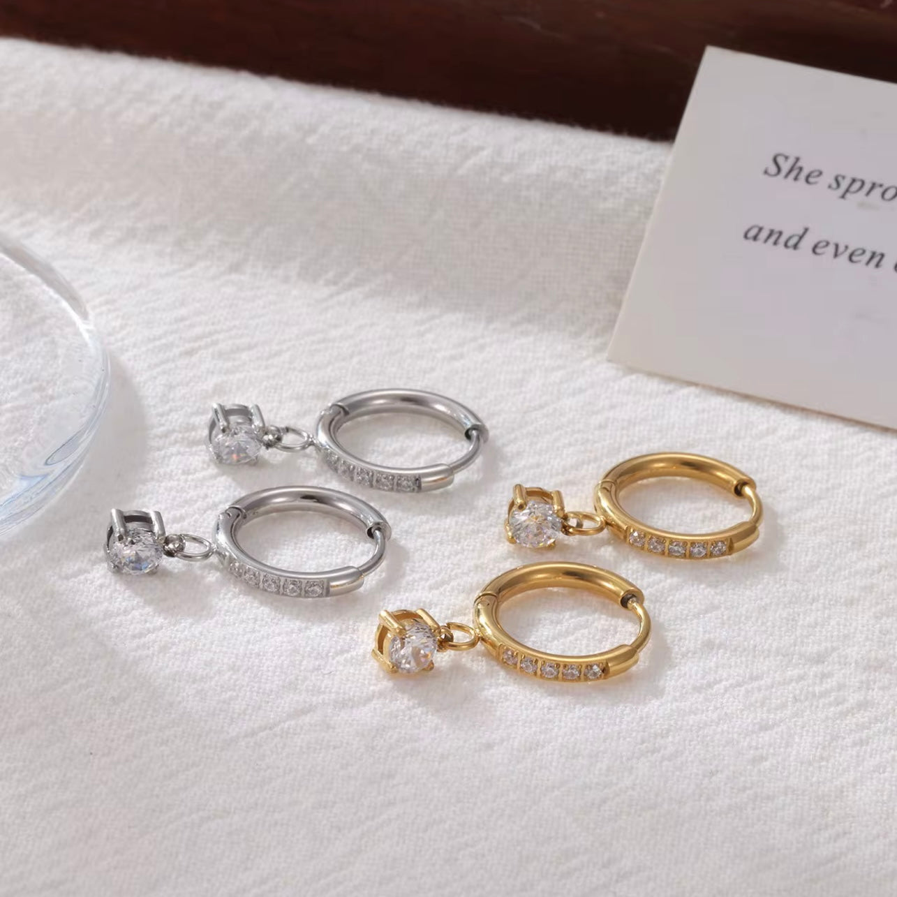 Gold and Silver hoop earrings with diamonds on the hoop and a round shaped drop pendant on a white background