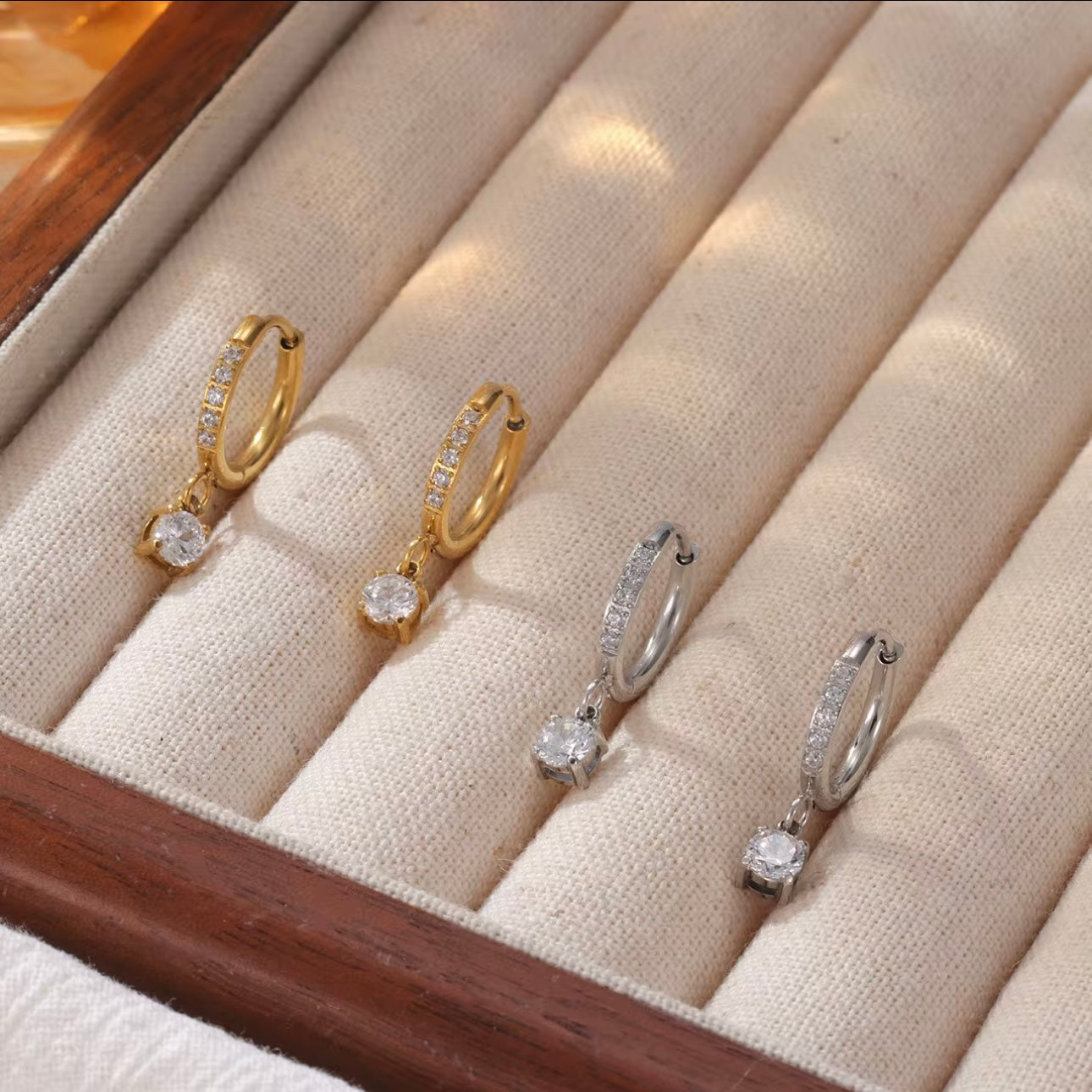 Gold and Silver hoop earrings with diamonds on the hoop and a round shaped drop pendant on a white background