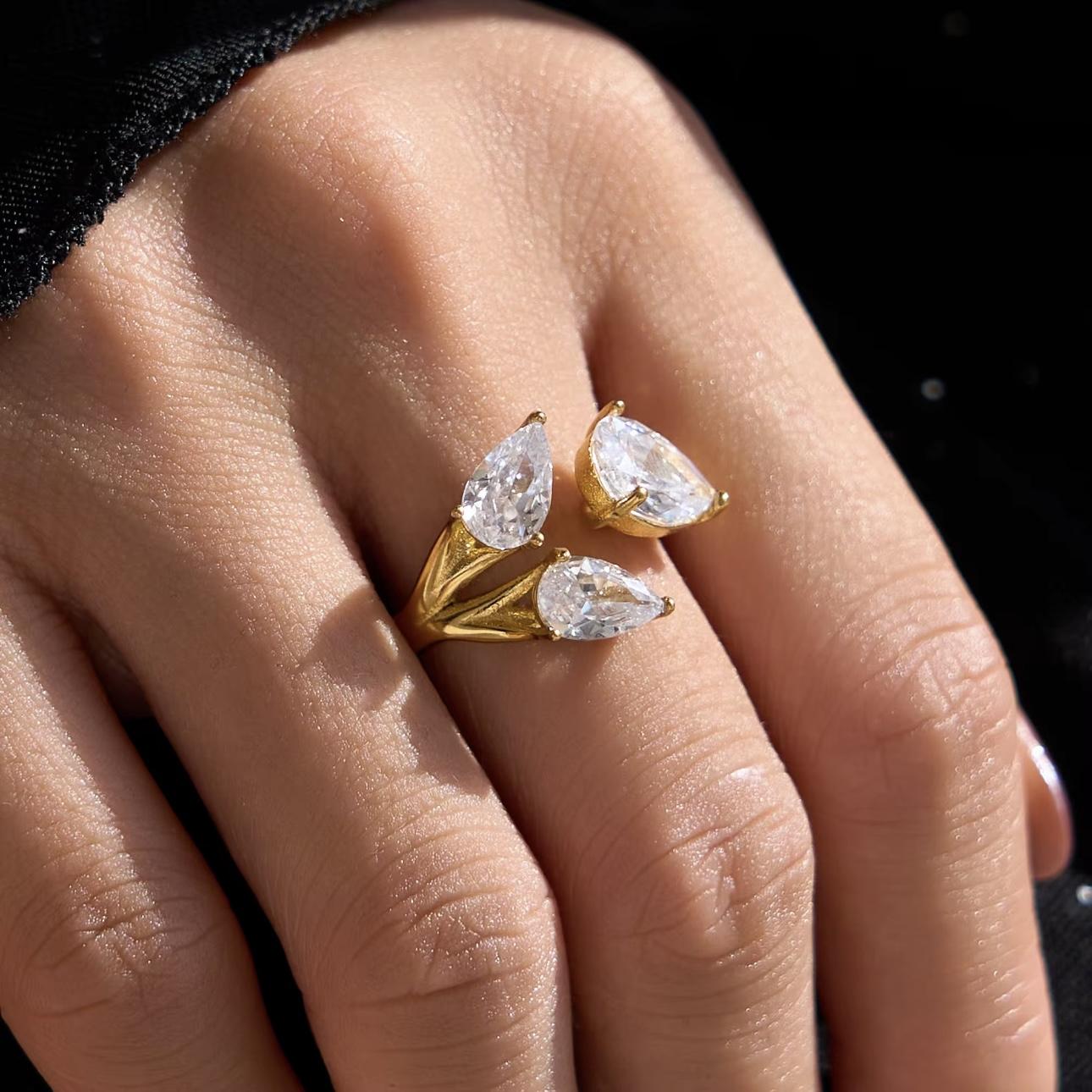 Gold ring with clear pear shaped gemstones on a hand