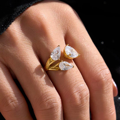 Gold ring with clear pear shaped gemstones on a hand