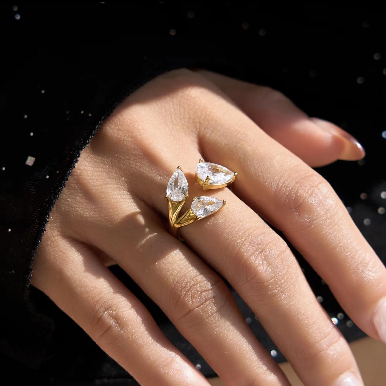 Gold ring with clear pear shaped gemstones on a hand