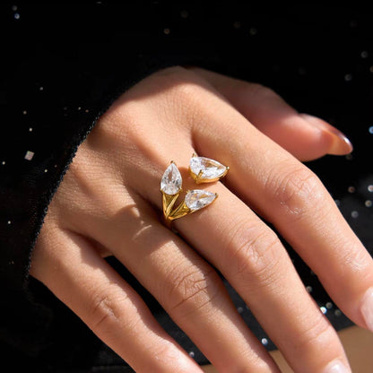 Gold ring with clear pear shaped gemstones on a hand