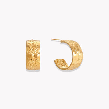 Gold earrings featuring intricate embossed detail pictured on a white background