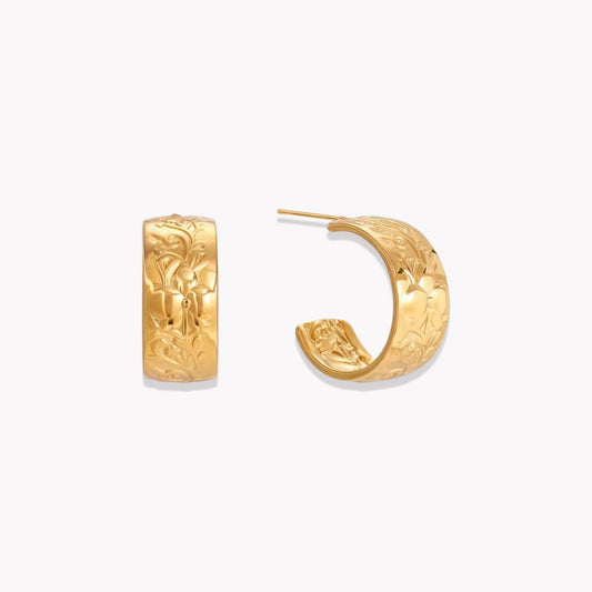 Gold earrings featuring intricate embossed detail pictured on a white background