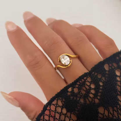 Gold ring with a diamond on a hand wearing a black lace sleeve.