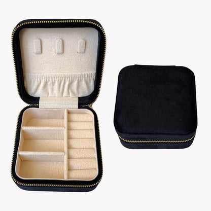 Black jewelry case with beige interior, open to reveal compartments.