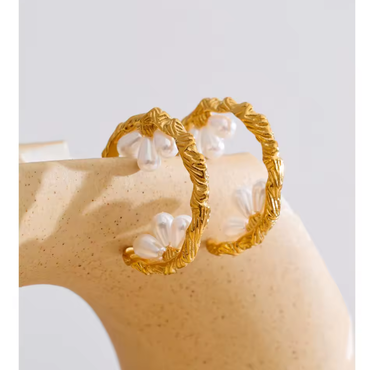 gold hooped earrings featuring pretty pearl detail photographed on a light background