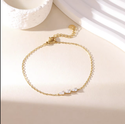 gold dainty bracelet with small pear shaped gemstone detail pictured on a neutral background