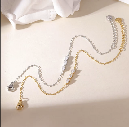 gold and silver dainty bracelets with small pear shaped gemstone detail pictured on a neutral background